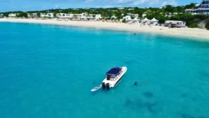 Private boat charter in Anguilla with guests swimming in clear turquoise water near beach