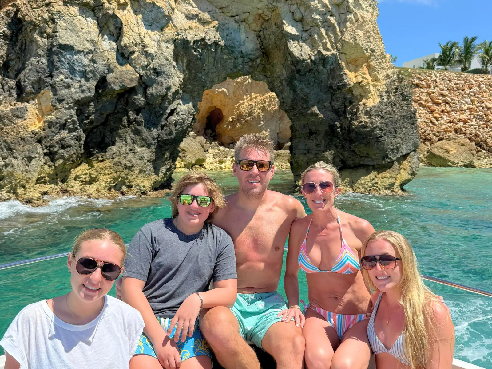 Family group on a private boat charter in St Maarten stopping to swim near rocky coastline