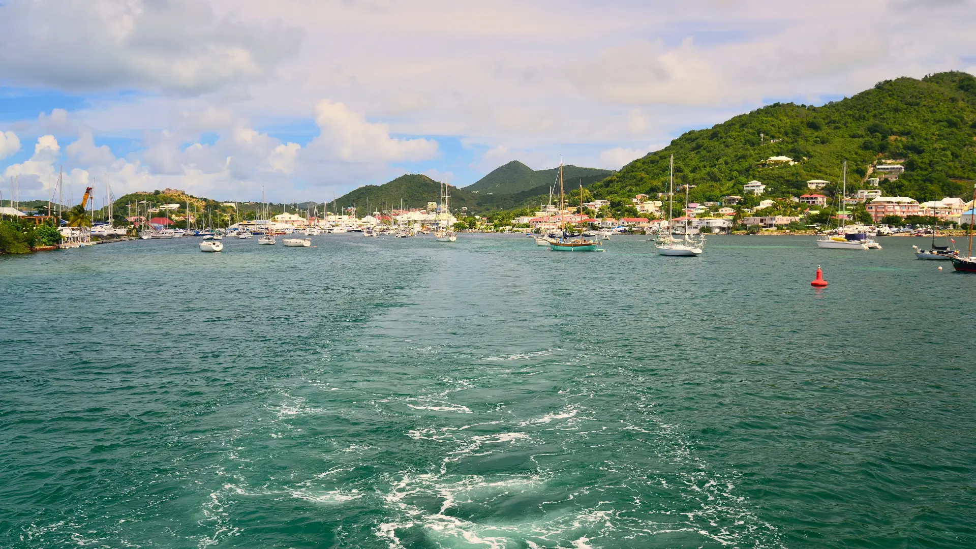 Boat leaving Simpson Bay Lagoon with mountains and marina in St Maarten