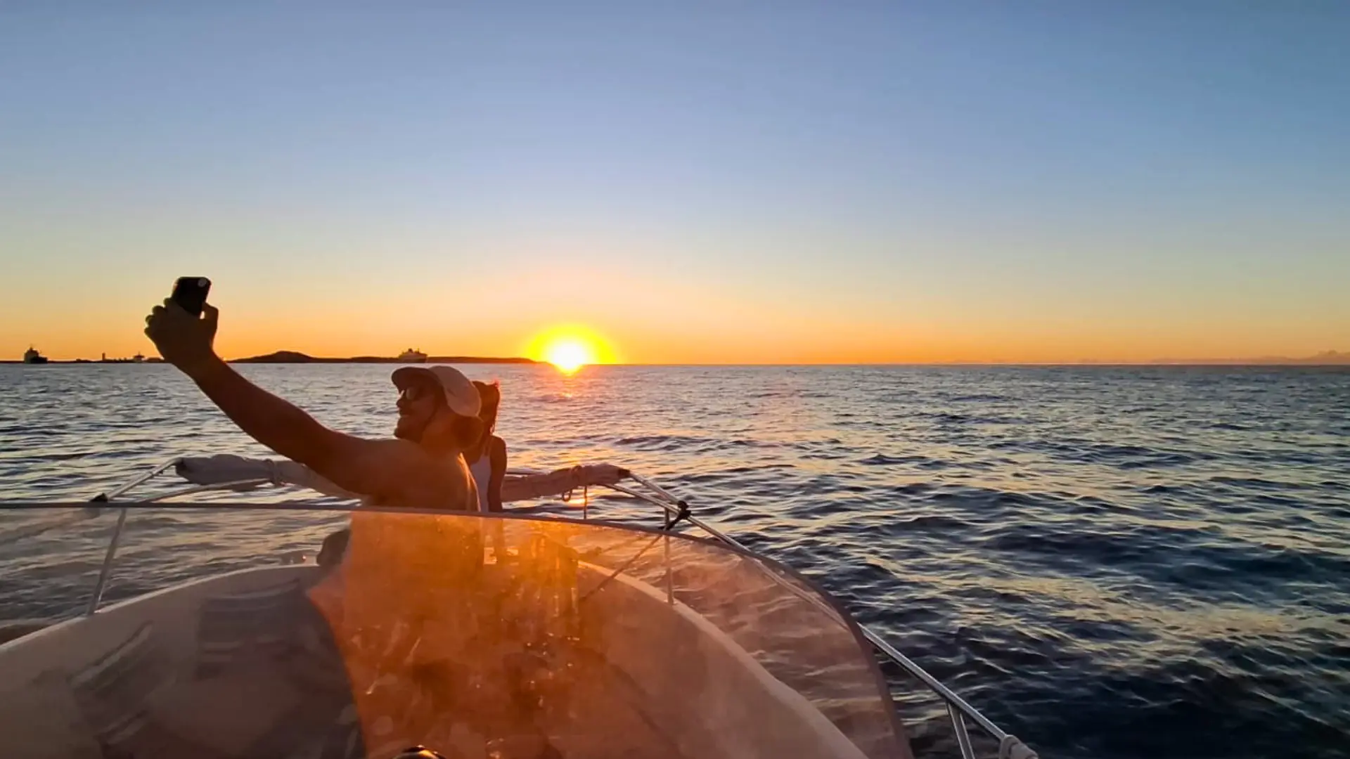 Two guests at bow of a private charter boat take a selfie together with the Caribbean sunset on the horizon in St Martin.