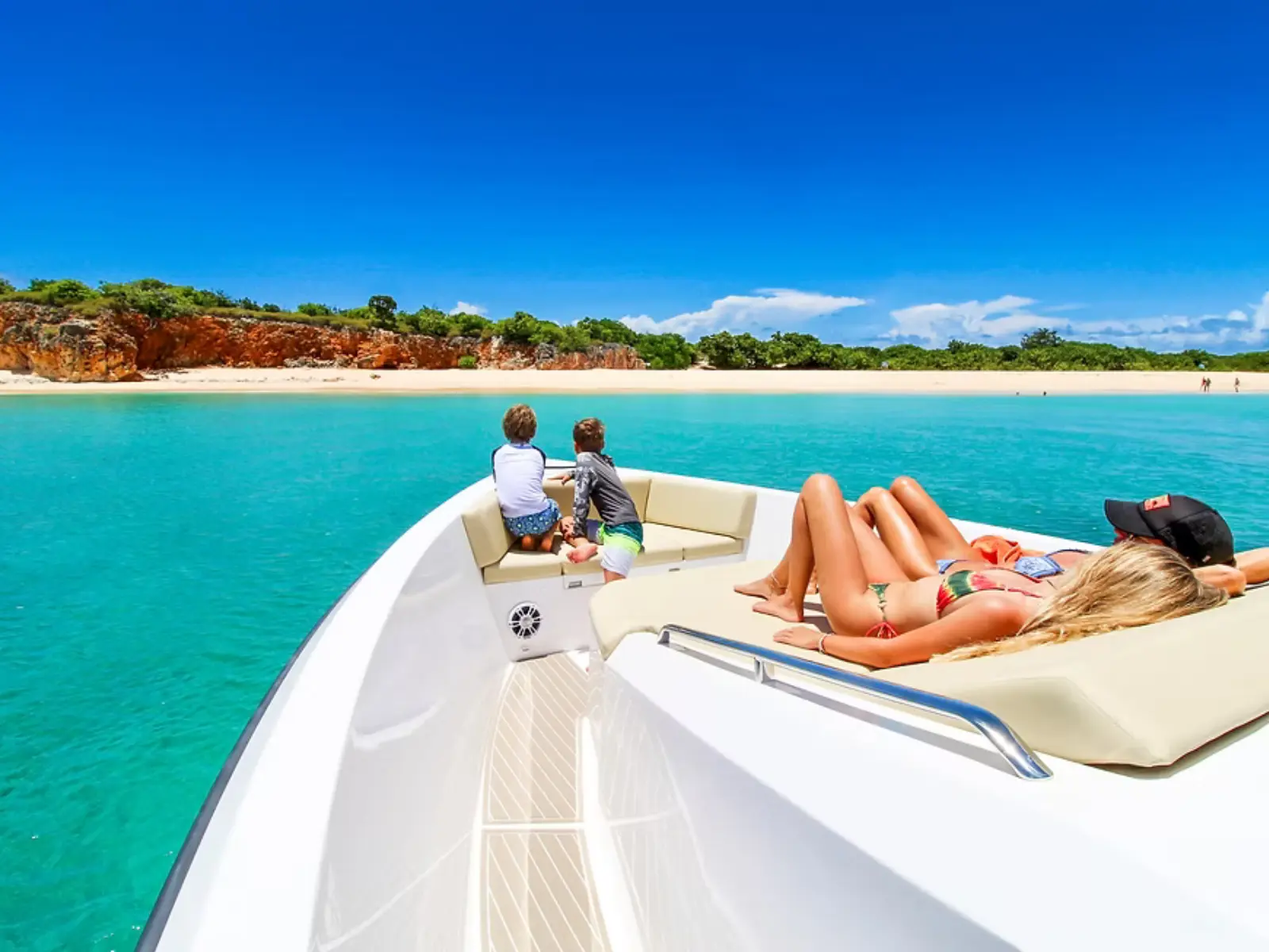 guests relaxing on front deck of private boat near sandy beach at Tintamarre, St Martin
