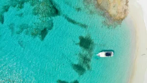 Aerial view of a private boat anchored in clear turquoise water near a quiet Caribbean beach in Anguilla during a St Maarten boat charter day trip.