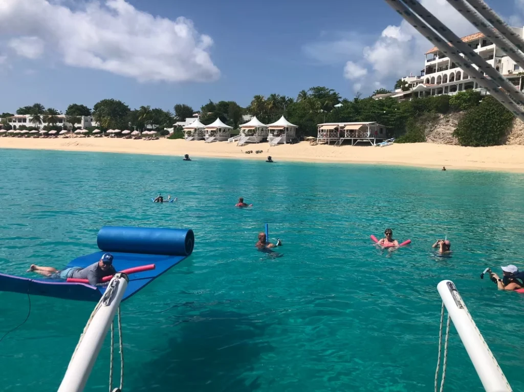 Guests swimming and relaxing beside a private sailing catamaran in St Maarten